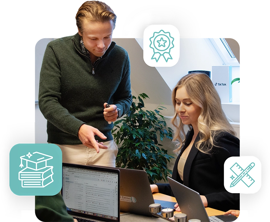 Blond manlig kollega instruerar kvinnlig kollega vid en laptop.